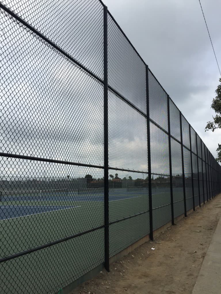 Black chain link fence around tennis courts