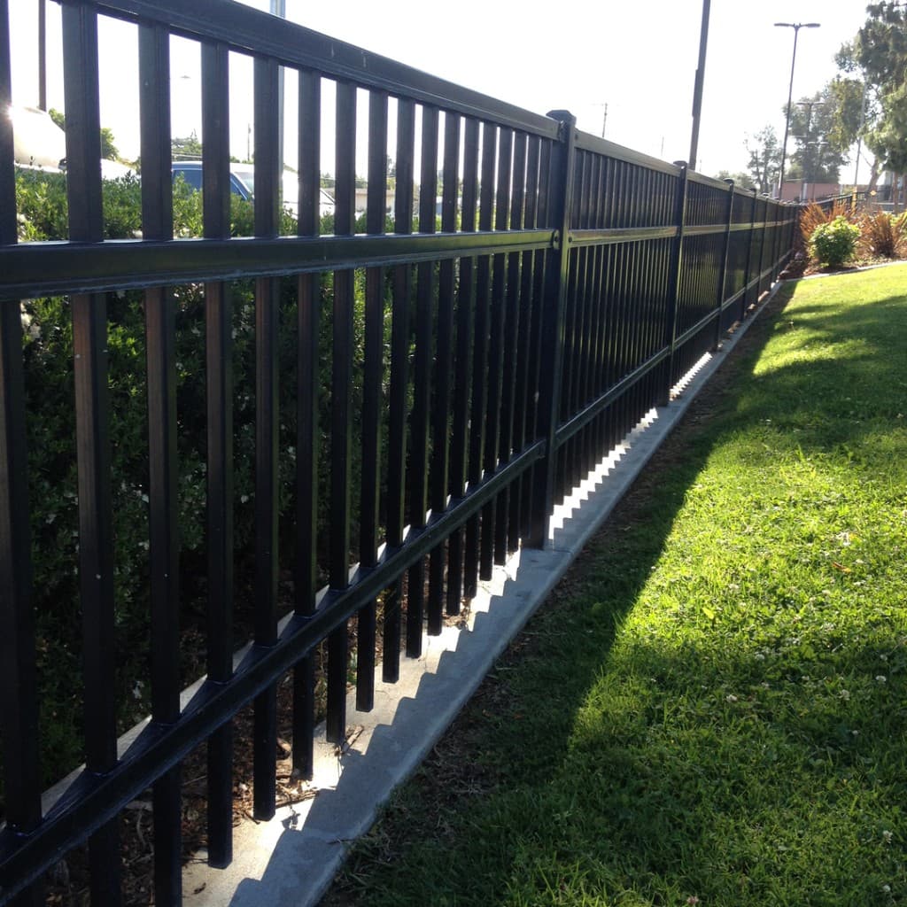 Two-rail ornamental iron fence beside landscaping